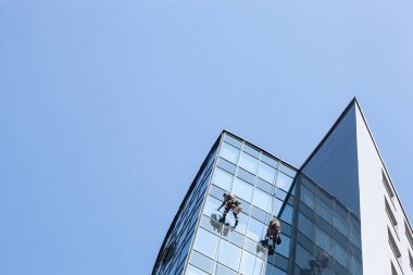 Yüksek binadaki pencereleri temizleyen bir grup işçi