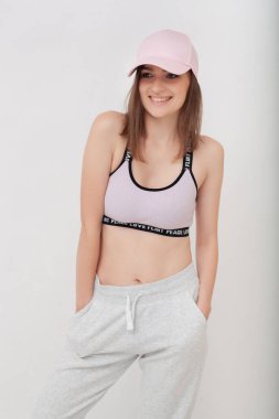 Spor takım elbiseli, spor ayakkabılı, beyaz stüdyo geçmişli çekici bir kadın. Beyaz arka planda esmerin spor stüdyosu portresi.