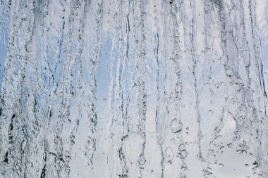 Mavi gökyüzüne karşı düşen şelalenin manzarası. Hareket halindeki donmuş suyun güzel dokusu.