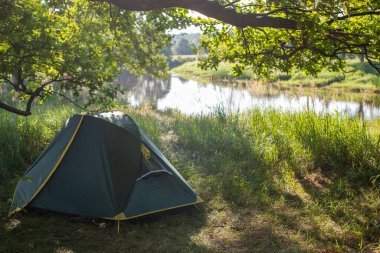 Yaz Parlak Sabahı 'nda çimlerin üzerinde çadır kurmak. Açık hava kamp macerası kavramı
