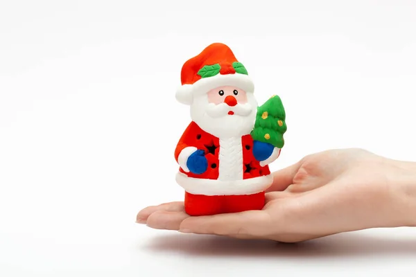 Kleines Weihnachtsmann-Spielzeug auf der Frauenhand isoliert auf weißem Hintergrund. Weihnachts- und Neujahrskonzept — Stockfoto