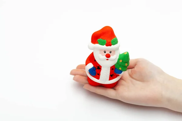 Маленькая игрушка Санта-Клауса на женской руке изолирована на белом фоне. Рождество и новая концепция года — стоковое фото