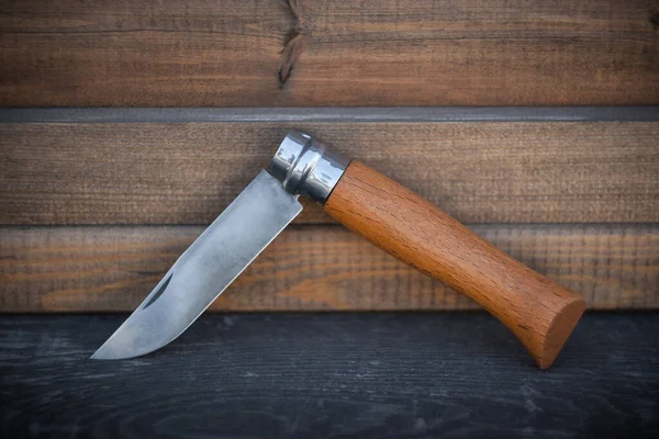 folding knife with wooden handle on wooden background