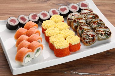 Suşi, ahşap bir masada beyaz kare bir tabakta yatar.