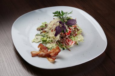 Beyaz tabakta tütsülenmiş et ile salata.