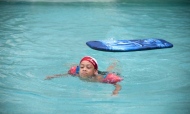 Çocuk havuzda yüzüyor.