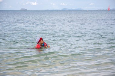 Çocuk denizde yüzüyor.