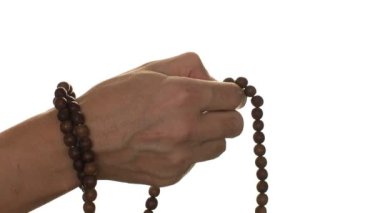 Hafif bir arka planda el, tespihin üzerinden geçer.