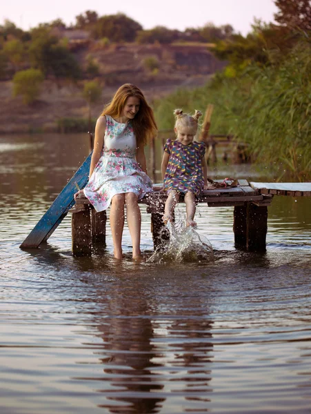 Mother and daughter sitting on the pier — Stock Photo, Image