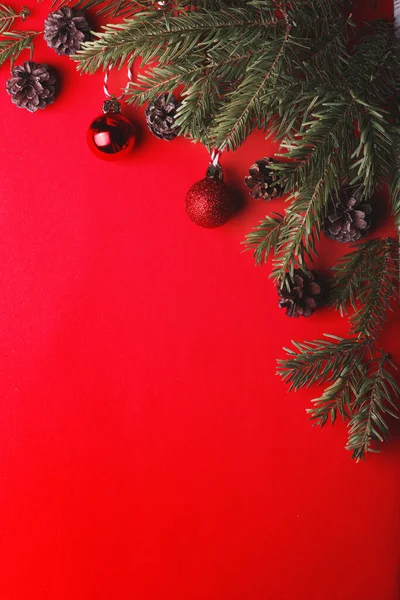 Ein Weihnachtlicher Hintergrund Tannenbaumzweige Weihnachtskugeln Und Zapfen Auf Rotem Hintergrund — Stockfoto