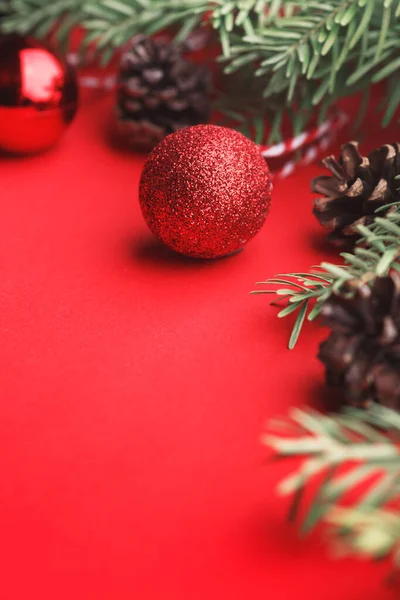 Ein Weihnachtlicher Hintergrund Tannenbaumzweige Weihnachtskugeln Und Zapfen Auf Rotem Hintergrund — Stockfoto