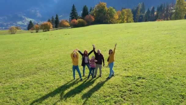 オーストリアアルプスの緑の秋の野原に立つ幸せな家族10月の晴れた日に手を振って — ストック動画