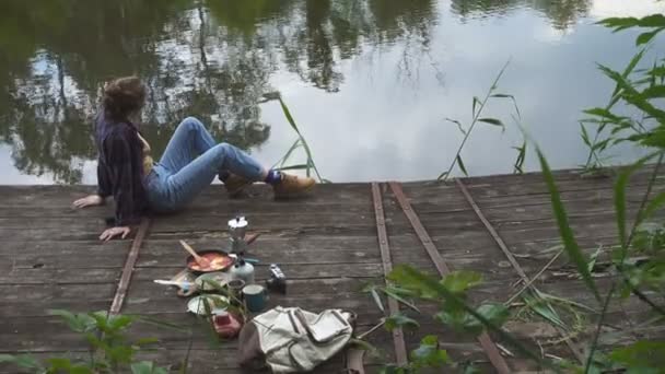 10代の女の子が川岸の木製の桟橋でピクニックをしていて — ストック動画