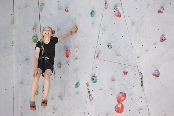 fun sport. bouldering, little smiling girl climbing up the wal