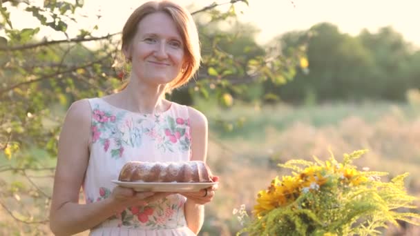 Uśmiechnięta Kobieta Trzymająca Dłoniach Domowe Ciasto Stojące Przy Stole Ogrodzie — Wideo stockowe