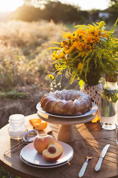 garden and still life. tea party in the garden -  peach pie, vase with bouquet of wildflowers on a tabl