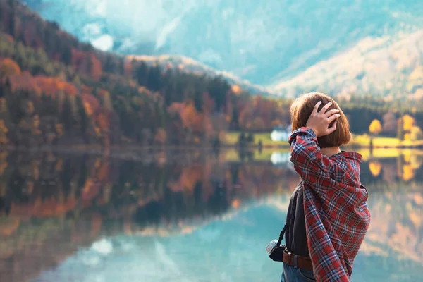 山の湖のほとりにはリュックを背負った少女が立っています — ストック写真