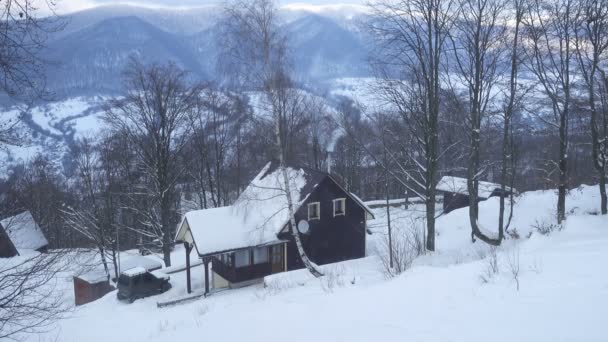 在冬日的早晨 雪山山上的木屋烟囱里冒着烟 — 图库视频影像