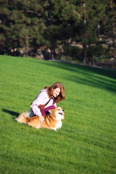 girl and dog corgi walking in the par