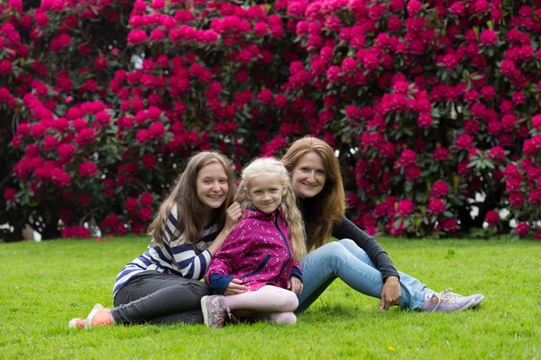 Mother with daughters sitting on a grass — Stock Photo, Image