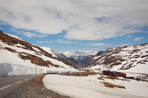 Karlı dağ yolu ve kırmızı evleri — Stok fotoğraf