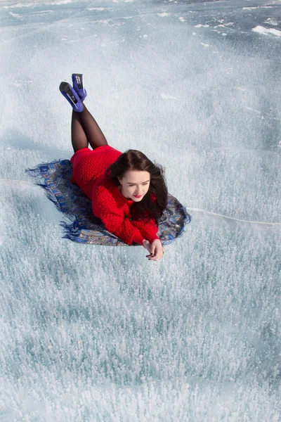 Молодая девушка в красном платье, лежащая на льду Байкала — стоковое фото