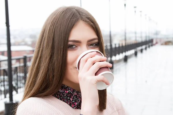 Chica joven bebiendo café al aire libre en clima inclemente — Foto de Stock