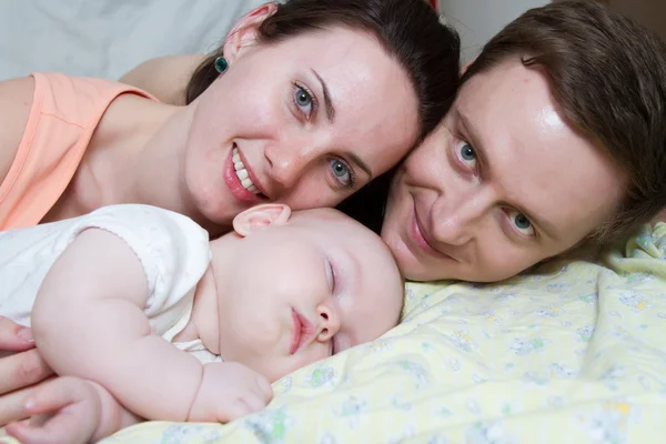 Padres felices cerca de un bebé dormido — Foto de Stock