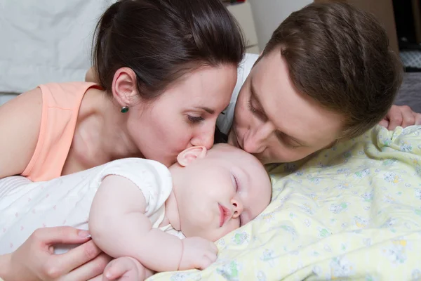 Padres felices cerca de un bebé dormido — Foto de Stock