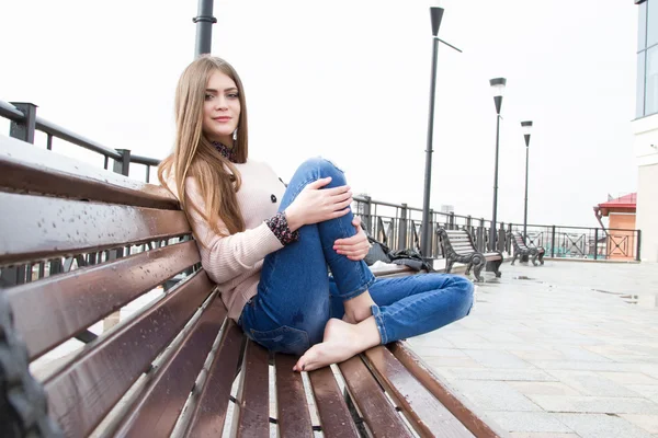Jeune fille aux cheveux longs assis sur le banc — Photo