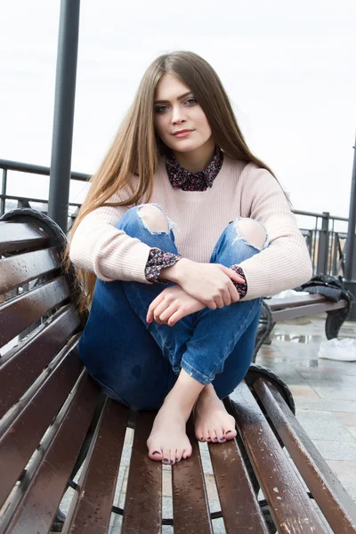 Chica joven con el pelo largo sentado en el banco — Foto de Stock