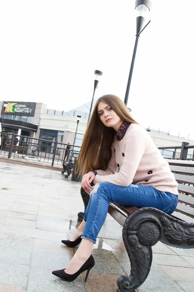 Fiatal lány ül a padon hosszú hajú — Stock Fotó