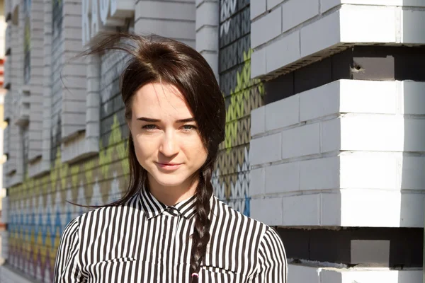 Mooie jonge vrouw in de mannen gestreept shirt staande op de hoek van het huis — Stockfoto