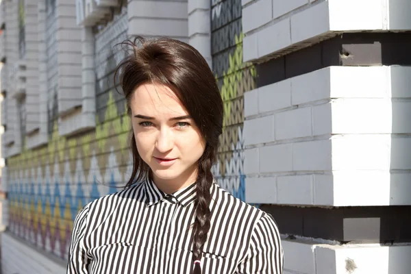 Mooie jonge vrouw in de mannen gestreept shirt staande op de hoek van het huis — Stockfoto