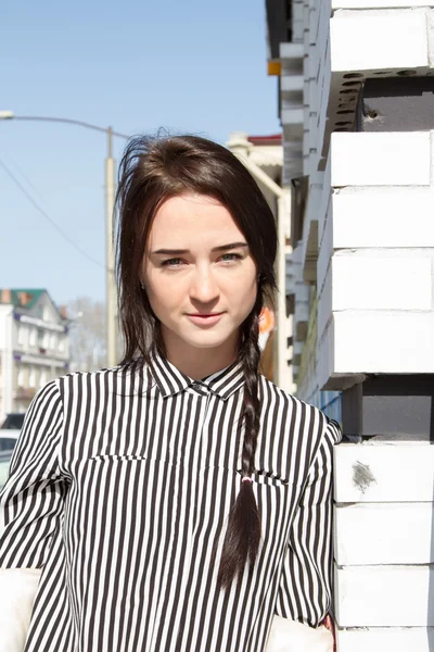 Hermosa mujer joven con la camisa a rayas de los hombres de pie en la esquina de la casa — Foto de Stock