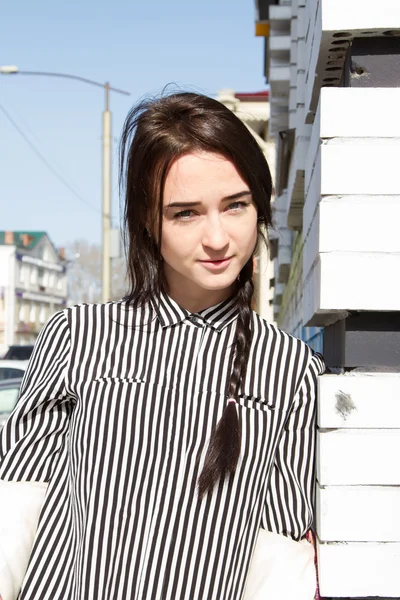 Hermosa mujer joven con la camisa a rayas de los hombres de pie en la esquina de la casa — Foto de Stock