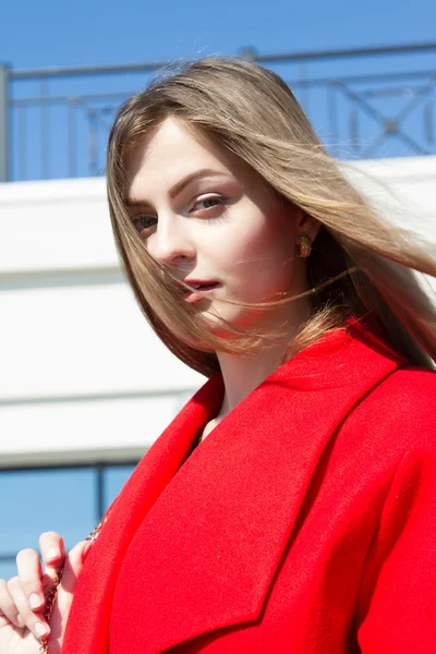 事務所ビルの背景に赤いコートで美しい少女 — ストック写真