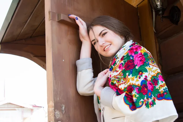 Mädchen mit Kopftuch vor dem Hintergrund eines Holzhauses — Stockfoto