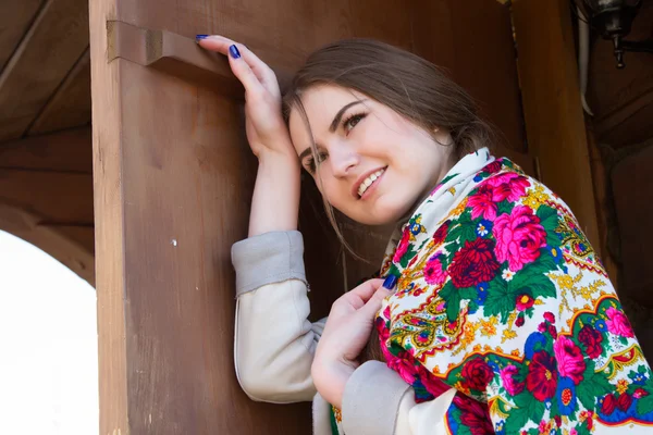 Chica con un pañuelo sobre el fondo de una casa de madera —  Fotos de Stock