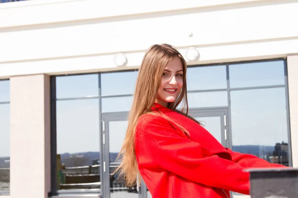 Ділова жінка в червоному пальто на тлі офісної будівлі — стокове фото