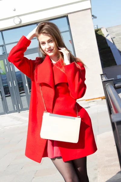 Zakenvrouw in een rode jas op de achtergrond van kantoorgebouw — Stockfoto