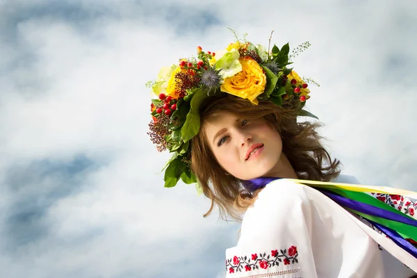 Flicka i ukrainska folkdräkt med en krans av blommor — Stockfoto