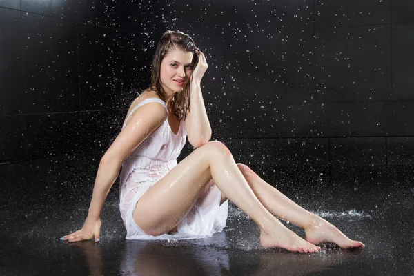 Mädchen in nassen Kleidern unter den Wasserstrahlen — Stockfoto
