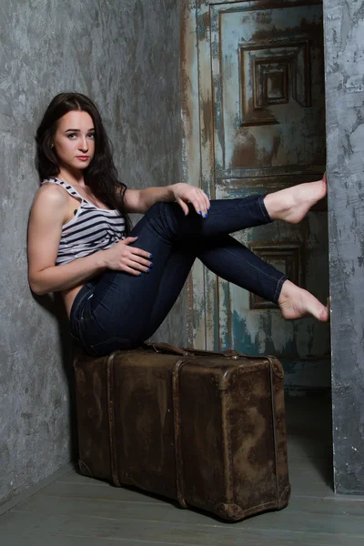 Young girl sitting on a huge old suitcase — Stock Photo, Image