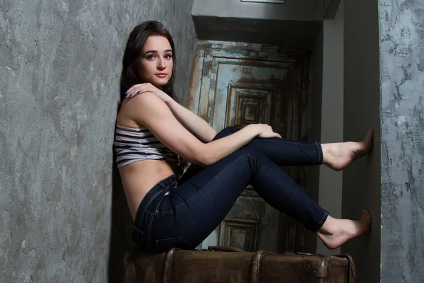 Young girl sitting on a huge old suitcase — Stock Photo, Image