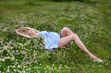 Genç hamile kadın yabani yonca kıyısında yatıyor