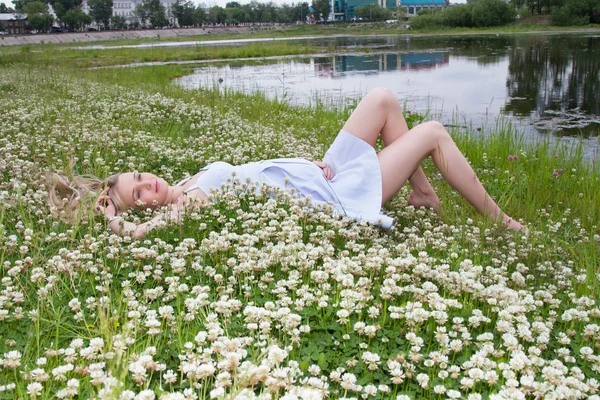 Young pregnant woman is lying on the shores of wild clover — Stock Photo, Image