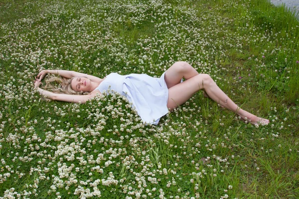 Young pregnant woman is lying on the shores of wild clover — Stock Photo, Image