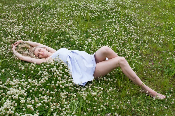 Young pregnant woman is lying on the shores of wild clover — Stock Photo, Image