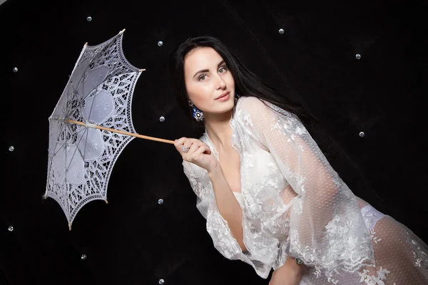 Girl in lacy underwear with an umbrella from the sun on a black background — Stock Photo, Image